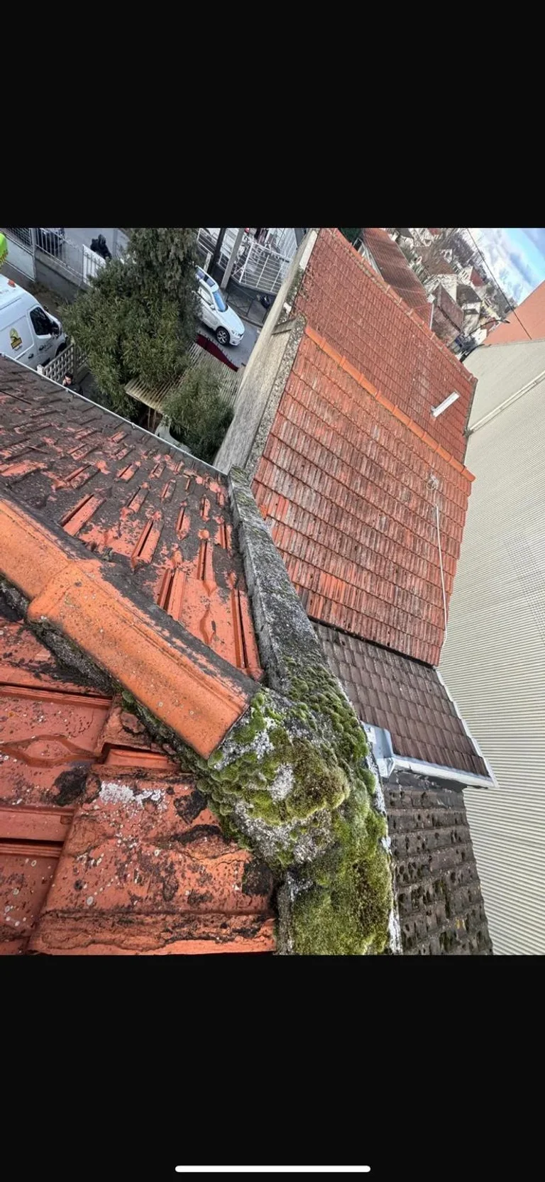 Mousse accumulée à la jonction d’une gouttière et d’un chéneau en tuiles, cause fréquente de débordement