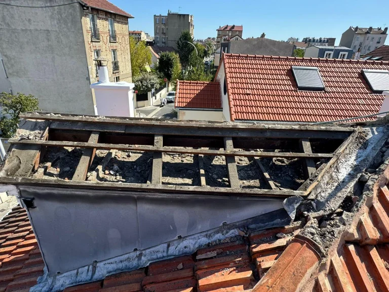 Charpente de toiture fragilisée et noircie par l’humidité autour d’une lucarne, après dépose de la couverture