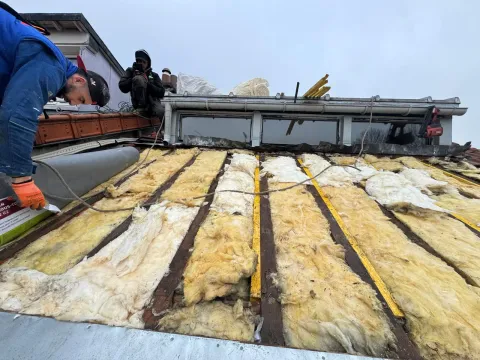Toiture déposée : ancienne isolation entre les chevrons et rouleau d’écran sous-toiture prêt à être posé par un couvreur