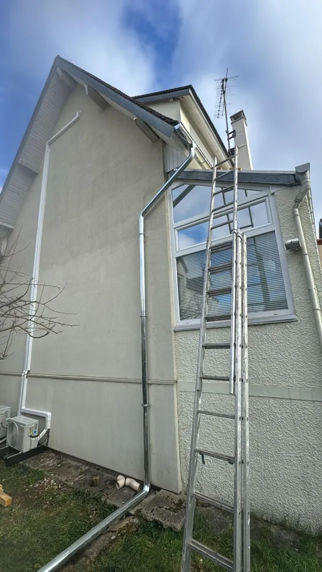 Descente d’eaux pluviales en zinc installée sur une façade à Houilles