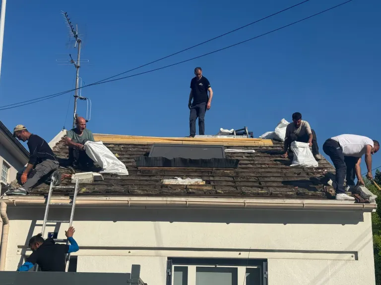 Équipe de couvreurs en pleine dépose de tuiles lors d'une rénovation de toiture à Argenteuil (95)