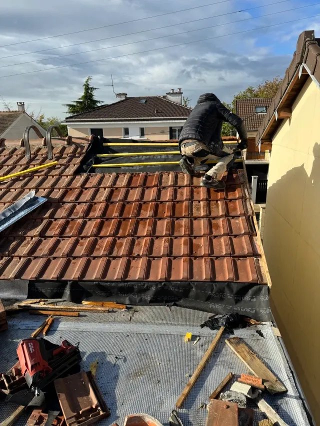Couvreur reposant des tuiles neuves après une intervention d’urgence toiture à Houilles