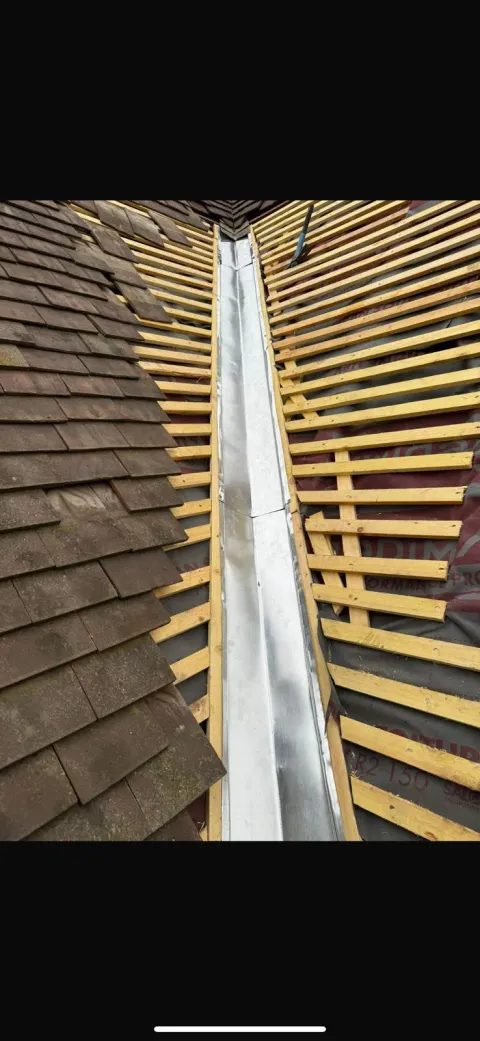 Chéneau en zinc façonné sur mesure et posé entre deux pans de toiture en tuiles